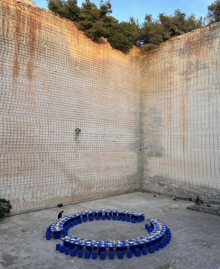 Circular blue dining installation against a tiled courtyard wall